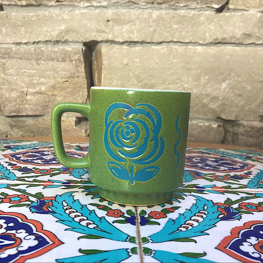 Green mug with blue flower outlines, and fancy swirl motifs